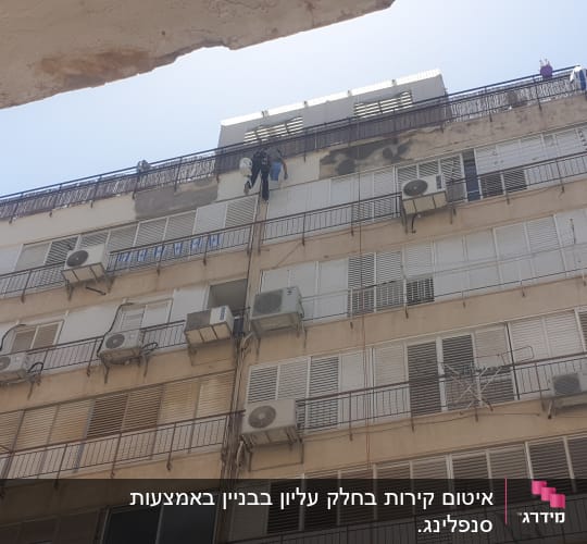אדם מבצע איטום על קיר חיצוני של בניין